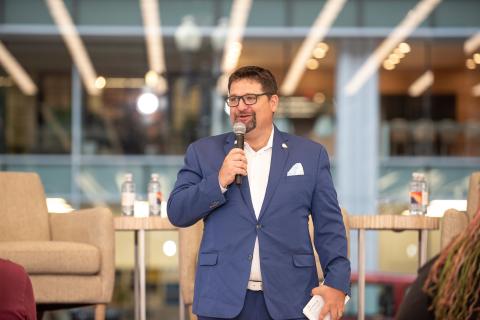 Man in blue suit stands with a microphone