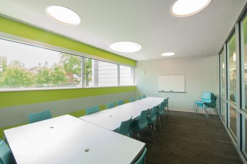 Room with two conference tables in a T position with blue chairs surrounding them