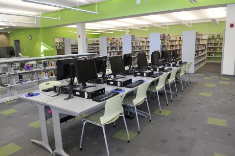 long row of tables with desktop computers on them