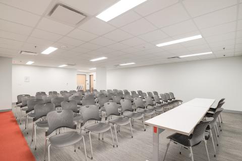 conference room with rows of black chairs seated in front of a table with four chairs