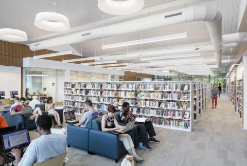 people sit in large chairs with books and computers with bookshelves behind them