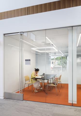 woman sits at a table in a meeting room with a glass door