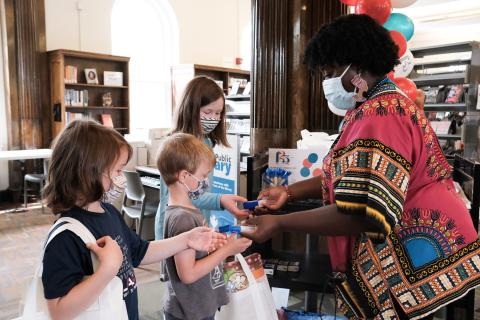Woman hands three children small items