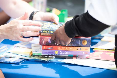 two sets of hands exchange a pile of books