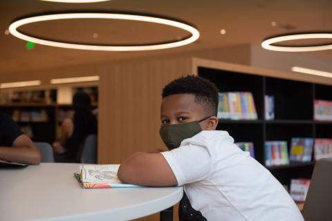Young boy sits at a table with an open book