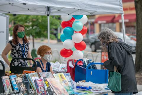 three women chat with each other over a table of books