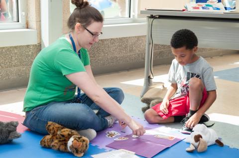 Woman sits on the floor with a young boy while they play