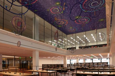 Large scale mobile of various round shapes and colors hanging from a purple ceiling