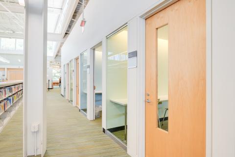 hallway with meeting room doors on the right and bookshelves on the left