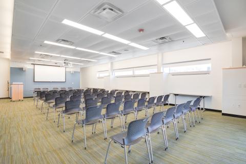 conference room with rows of black chairs in front of a projector screen