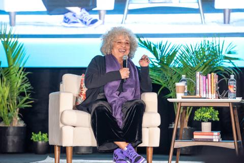 Angela Davis sits on a stage speaking into a microphone