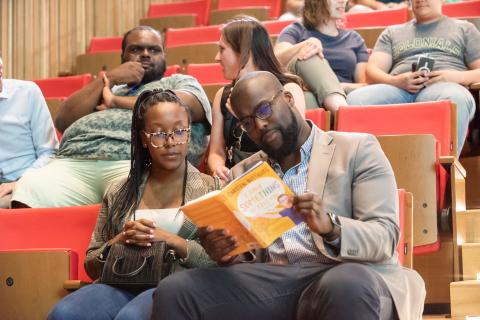 two people sit in the audience looking at a book