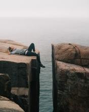 A girl lying on a cliff with a gap seperating it from the next cliff