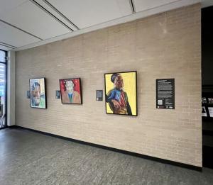 Installation view of three colorful portraits hung on a wall in the MLK Library