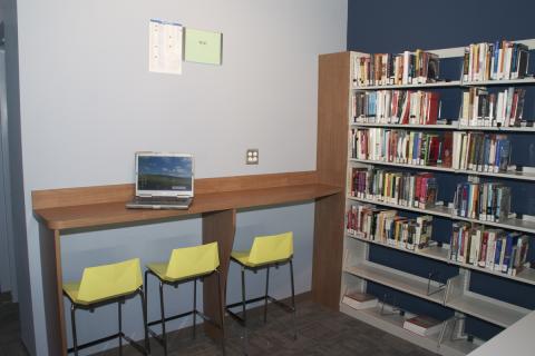 hightop table with three chairs next to a bookshelf