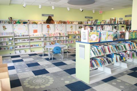 view into children's reading room with low bookshelves and tables and chairs
