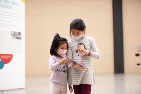 Two little girls read a book together