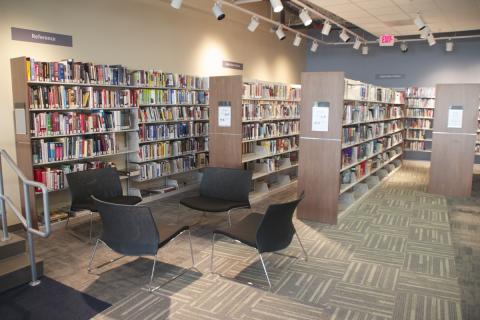 four black chairs in a circle in front of bookshelves