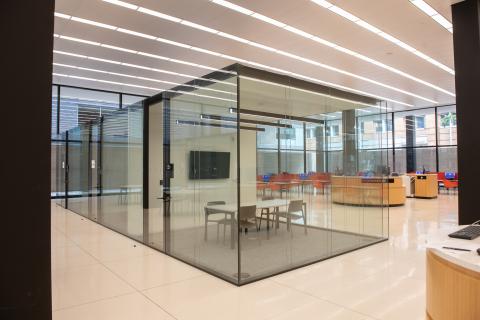 Table with four chairs and a TV situated in the middle of a glass box room