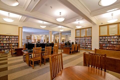Room surrounded by bookshelves with tables and chairs in the middle 