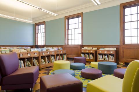 room with low bookshelves and bright colored round seating cushions 
