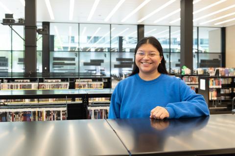 Woman smiling standing among bookshelves in the library