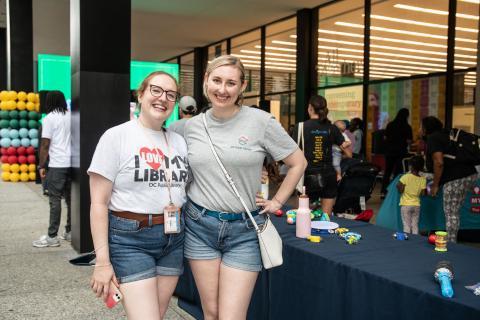 two women smile at the camera with their arms around eachother