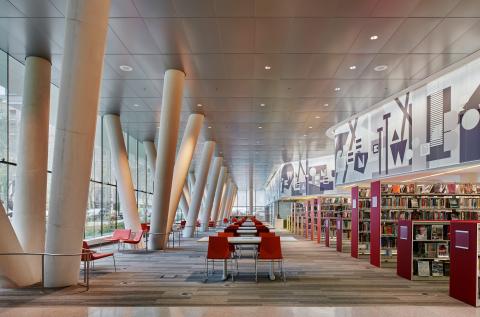overview of main room with industrial pillars on one side, bookshelves on the other, and tables in the middle