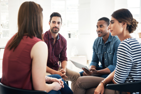 four adults sit in a circle talking with one another