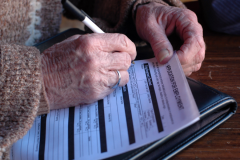 two hands fill out a job application with a pen