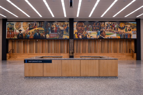 information desk sits in the middle of a large room with marble floor. A mural of Martin Luther King Jr. and other activists hangs above.