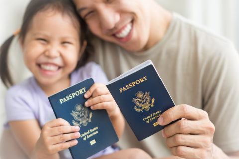 father and daughter smile while holding their passports