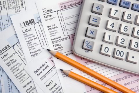 scattered tax forms, two yellow pencils and a calculator