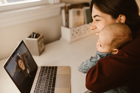 a mother and baby facetime on a computer with another person